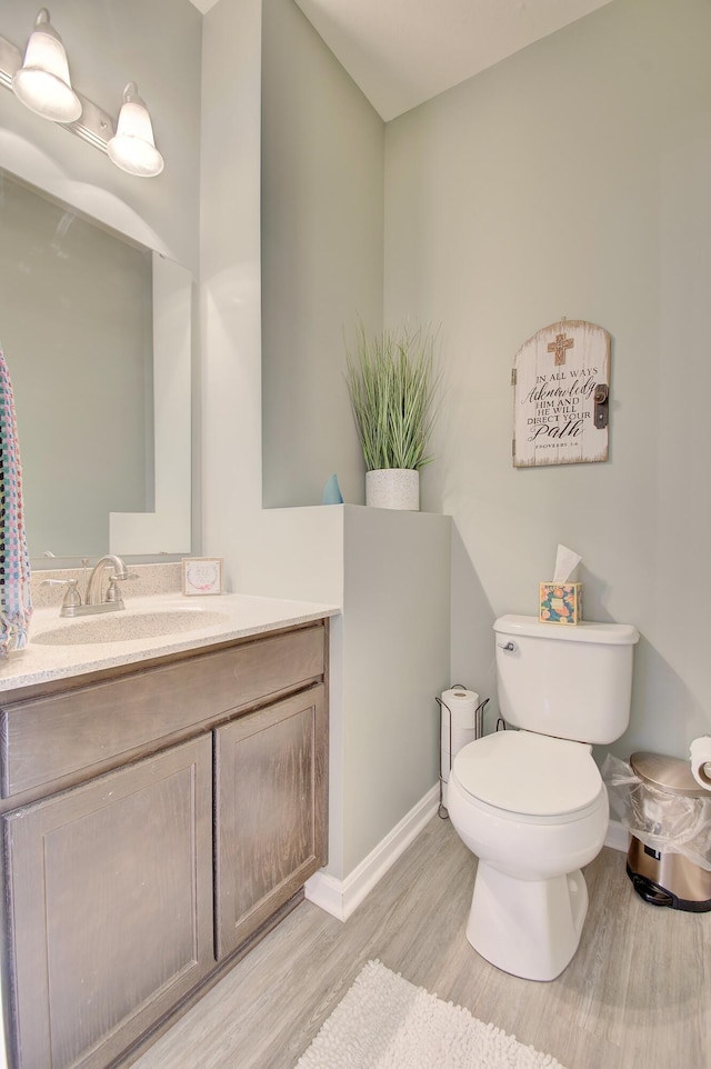 bathroom with baseboards, vanity, toilet, and wood finished floors