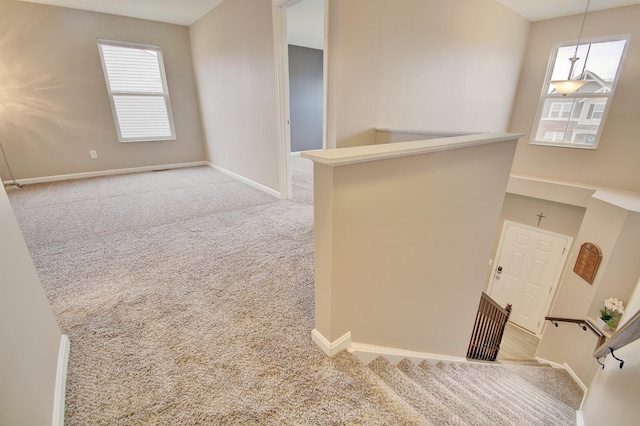 spare room featuring light carpet and baseboards