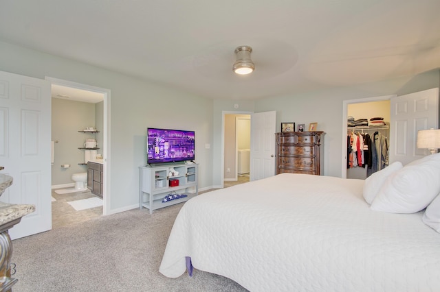 bedroom with connected bathroom, light colored carpet, baseboards, a closet, and a walk in closet