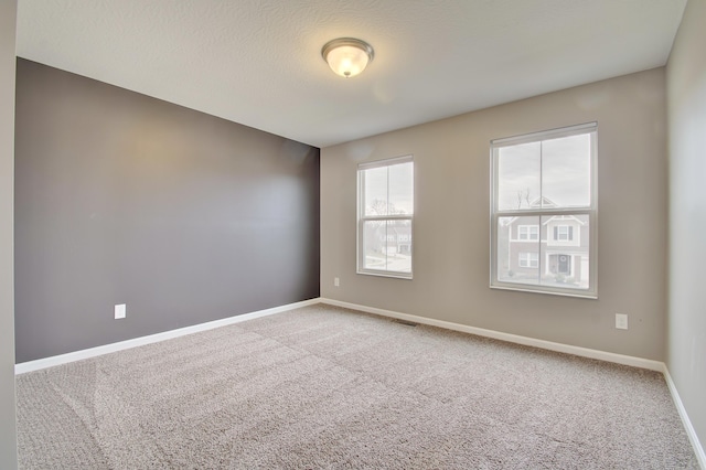 unfurnished room with visible vents, a textured ceiling, baseboards, and carpet flooring