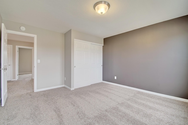 unfurnished bedroom with a closet, carpet flooring, and baseboards