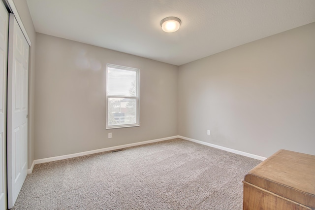 unfurnished bedroom with a closet, carpet, visible vents, and baseboards