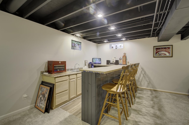 bar with baseboards, a sink, light colored carpet, and wet bar