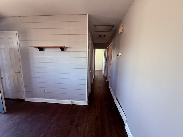 hallway featuring visible vents, wood finished floors, and baseboards