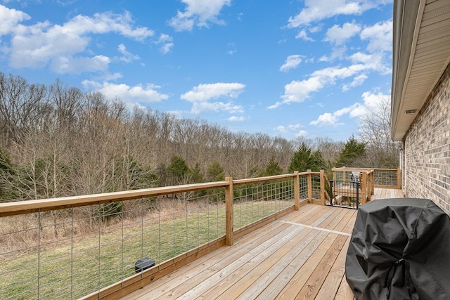 deck with a wooded view and a grill