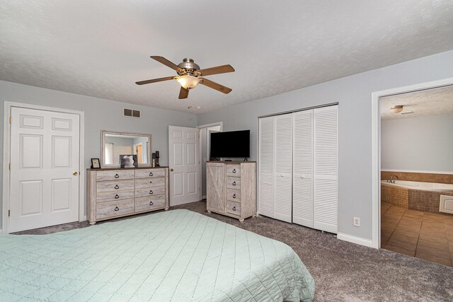 carpeted bedroom featuring visible vents, a ceiling fan, a textured ceiling, ensuite bath, and a closet