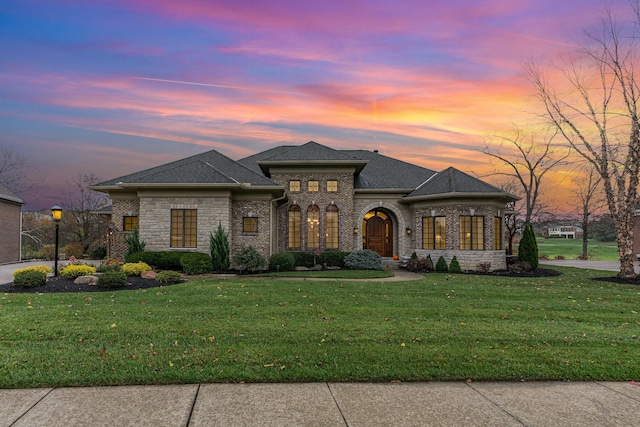 view of front facade featuring roof with shingles and a front lawn