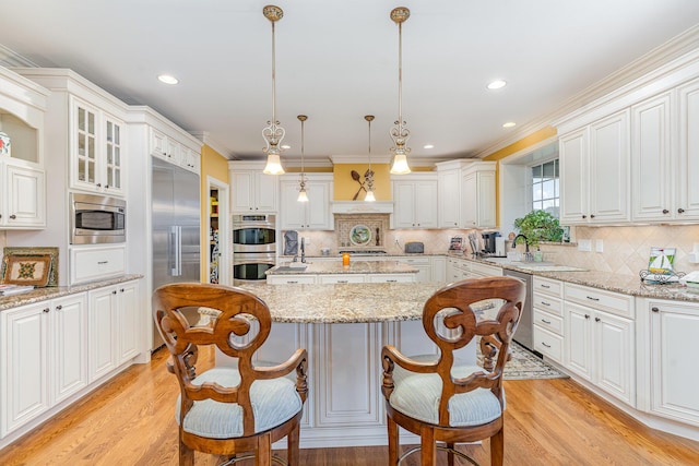 kitchen with built in appliances, light wood-style flooring, a center island, and white cabinets