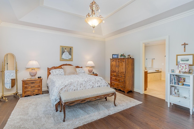 bedroom with dark wood-type flooring, connected bathroom, a raised ceiling, and ornamental molding