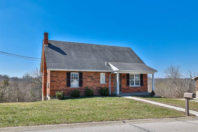 view of front of home featuring brick siding, a chimney, a front lawn, and a shingled roof