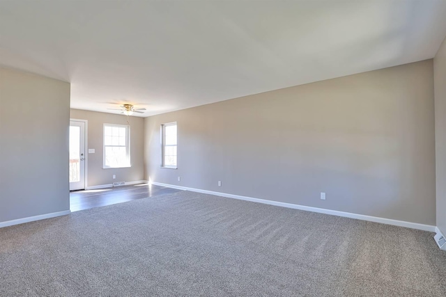 spare room with baseboards, a ceiling fan, and dark carpet