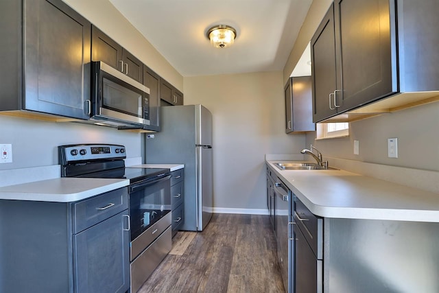 kitchen with light countertops, dark wood-type flooring, appliances with stainless steel finishes, and a sink