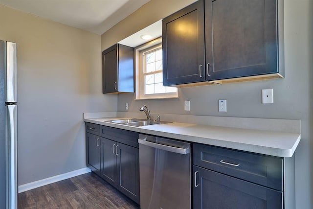 kitchen with baseboards, dark wood finished floors, light countertops, appliances with stainless steel finishes, and a sink