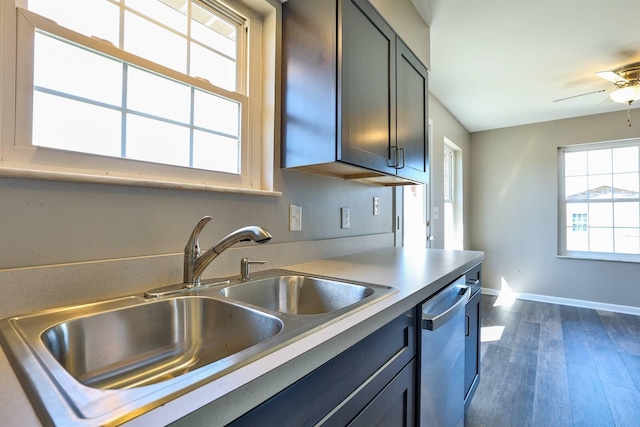 kitchen with dark wood-style floors, baseboards, a sink, light countertops, and stainless steel dishwasher