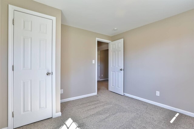 unfurnished bedroom with baseboards and carpet