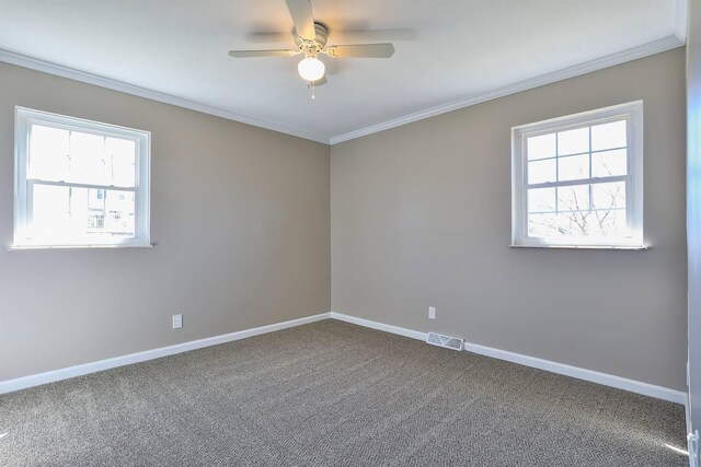 spare room featuring visible vents, a healthy amount of sunlight, crown molding, and baseboards