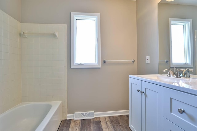 bathroom featuring visible vents, baseboards, wood finished floors, vanity, and  shower combination