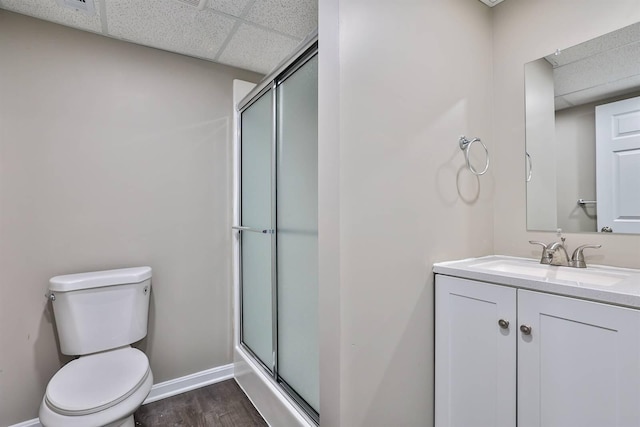 bathroom featuring a shower stall, toilet, a paneled ceiling, and baseboards