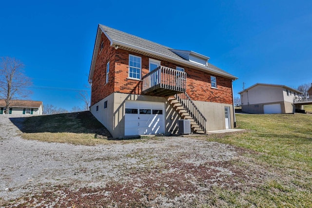 back of house featuring brick siding, stairs, central AC, a lawn, and an attached garage