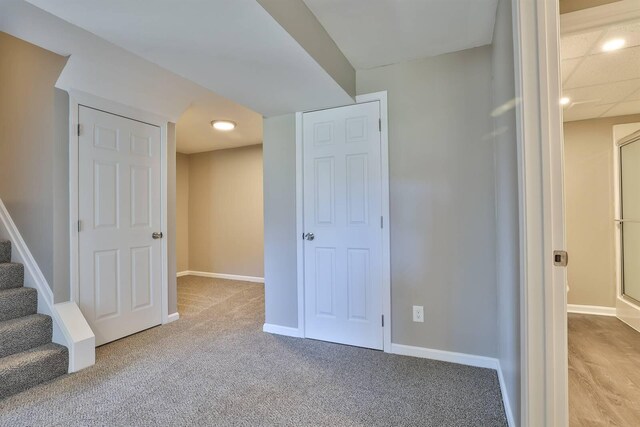 basement with stairway, baseboards, and light colored carpet