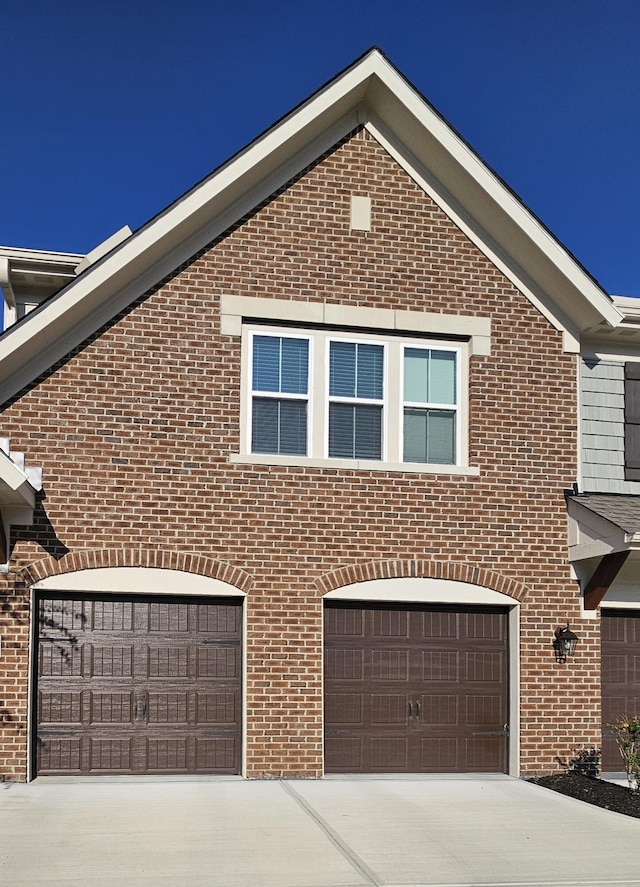 view of front facade with a garage, brick siding, and driveway