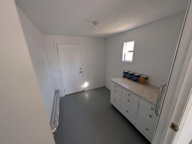 interior space with a textured ceiling and concrete flooring