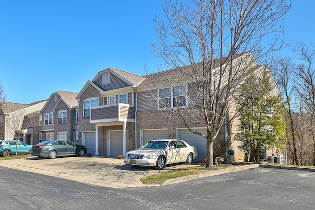 multi unit property with brick siding, a garage, and driveway