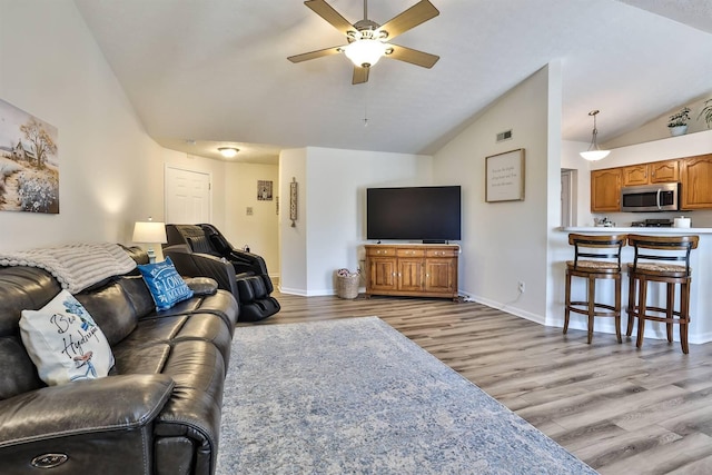 living room with a ceiling fan, lofted ceiling, baseboards, and light wood-type flooring