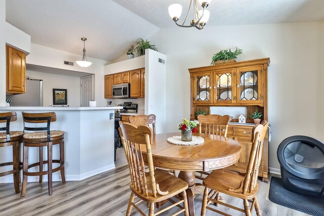 dining area with light wood-style flooring, baseboards, lofted ceiling, and an inviting chandelier