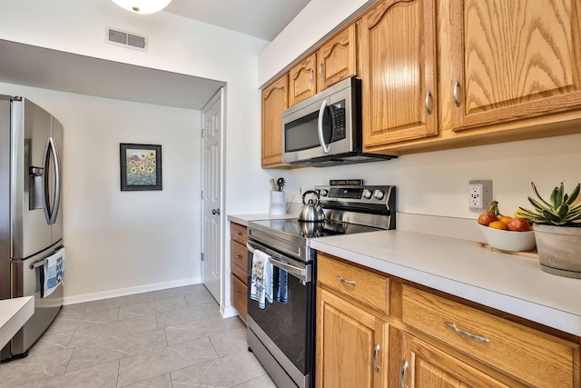 kitchen with visible vents, appliances with stainless steel finishes, brown cabinetry, light countertops, and baseboards