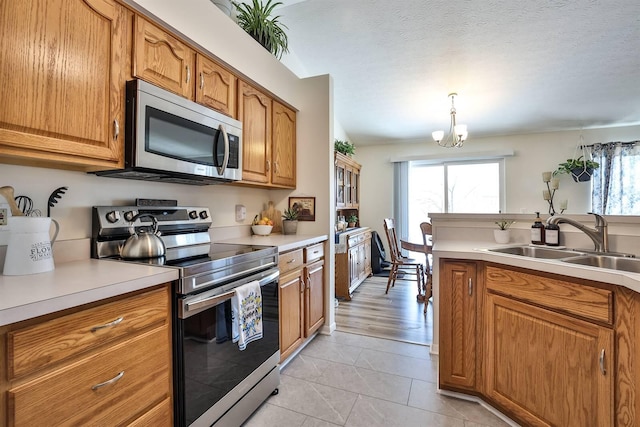 kitchen with light countertops, brown cabinetry, appliances with stainless steel finishes, and a sink