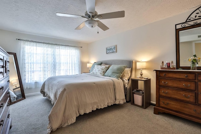 bedroom featuring baseboards, light carpet, a textured ceiling, and ceiling fan