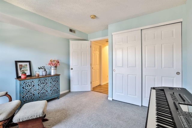 living area with visible vents, baseboards, carpet, and a textured ceiling