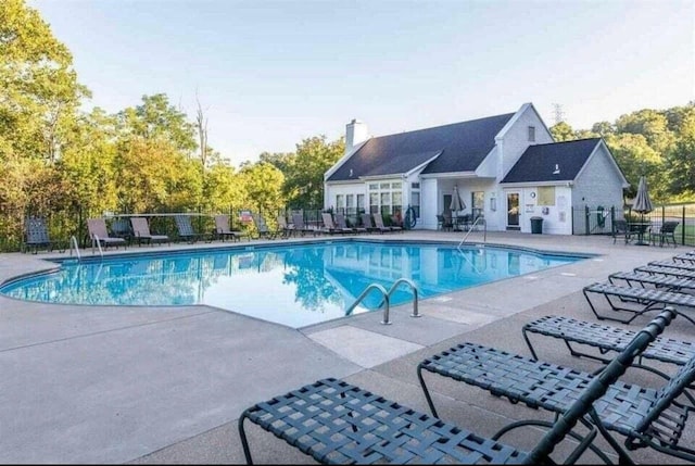 community pool with a patio and fence