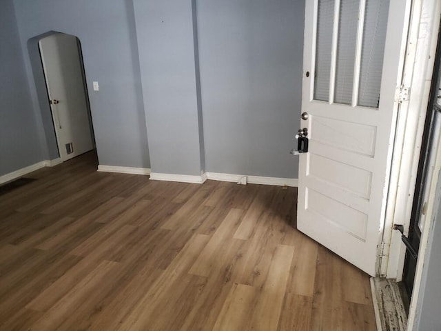 spare room with baseboards and wood finished floors