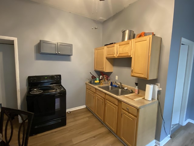 kitchen featuring light wood finished floors, baseboards, light countertops, electric range, and a sink