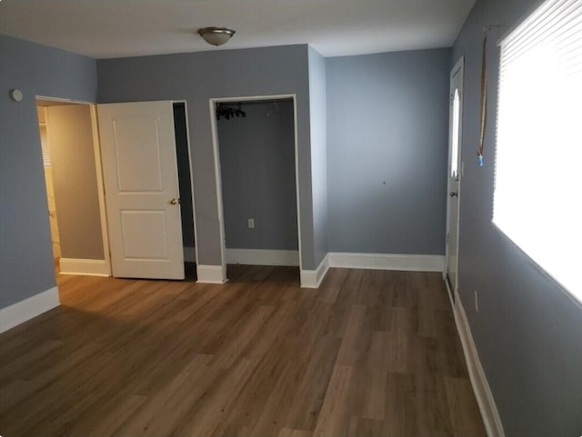 unfurnished bedroom featuring wood finished floors, baseboards, and two closets