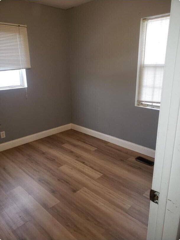 empty room with visible vents, baseboards, and wood finished floors