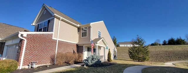 view of side of property featuring a garage, brick siding, and a shingled roof