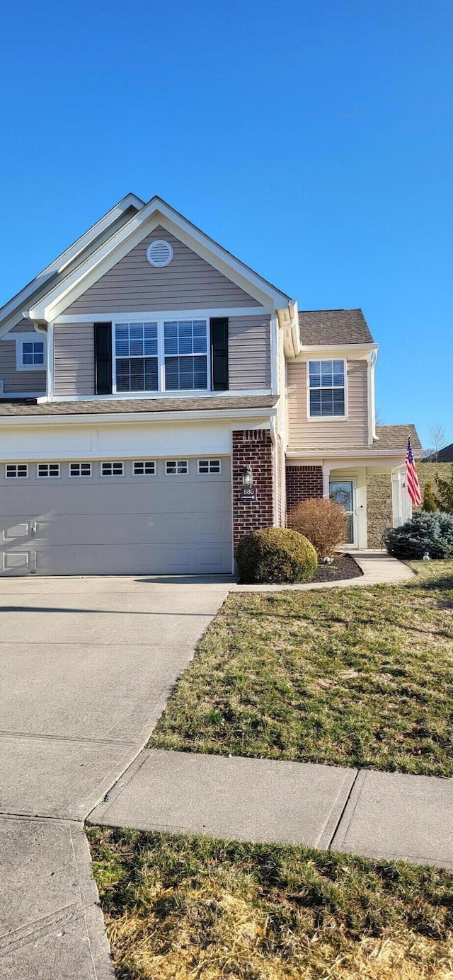 traditional-style house with brick siding, driveway, an attached garage, and a front lawn