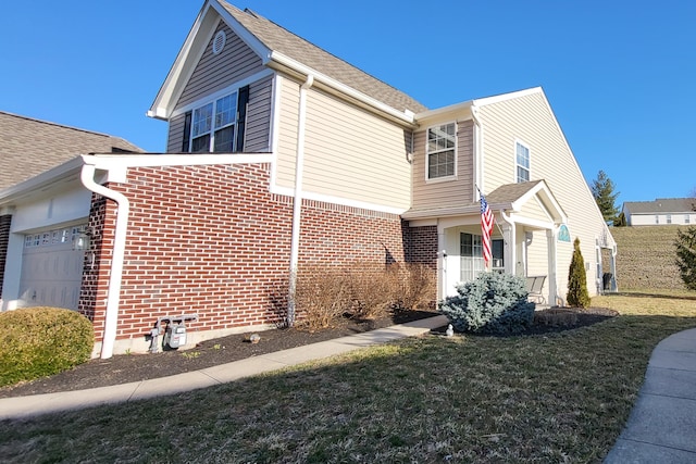 view of side of property with a yard, brick siding, roof with shingles, and an attached garage