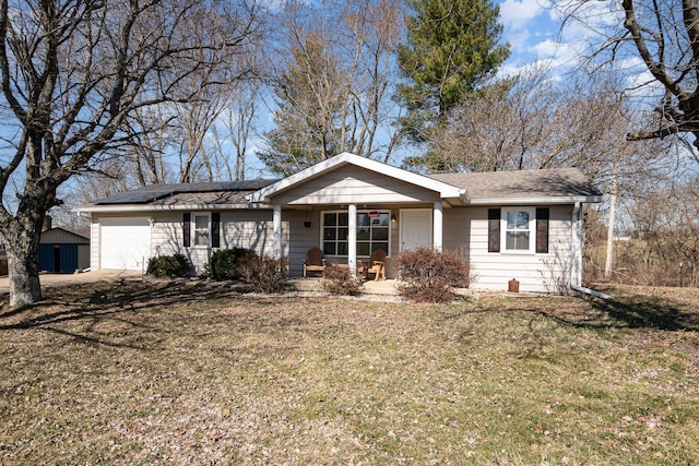 ranch-style home featuring a front yard, roof with shingles, covered porch, a garage, and roof mounted solar panels