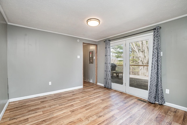 spare room with visible vents, ornamental molding, a textured ceiling, light wood-style floors, and baseboards