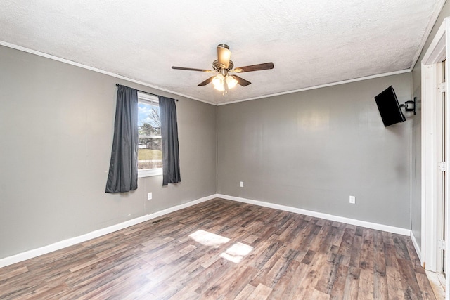 spare room featuring a textured ceiling, crown molding, baseboards, and wood finished floors