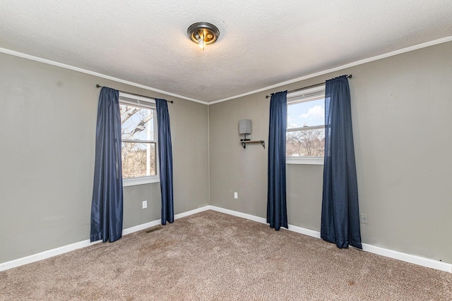 carpeted spare room with baseboards, a textured ceiling, a healthy amount of sunlight, and ornamental molding