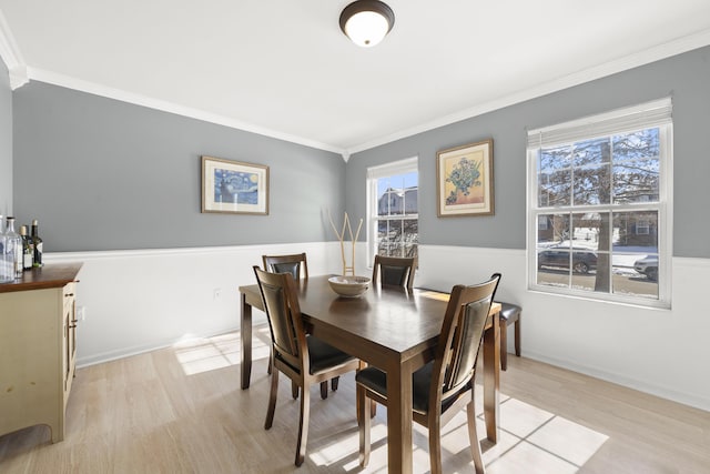 dining space with crown molding, light wood-style flooring, and a wealth of natural light