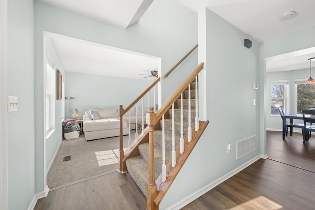 staircase with wood finished floors, visible vents, and baseboards