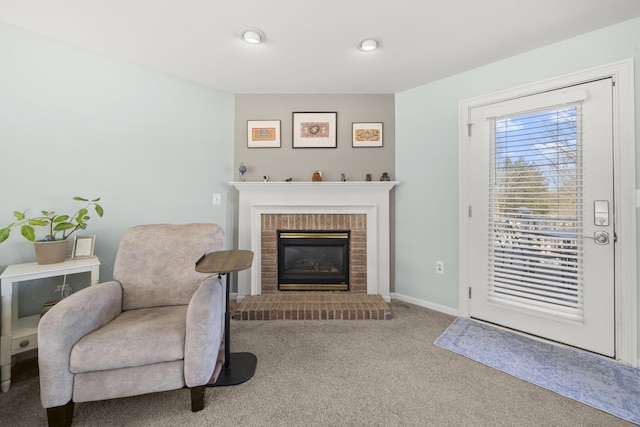 sitting room with a brick fireplace, baseboards, and carpet floors