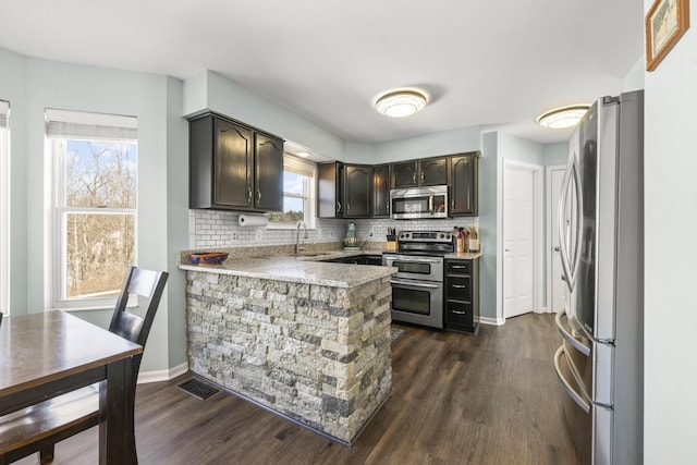 kitchen with visible vents, tasteful backsplash, appliances with stainless steel finishes, and a peninsula