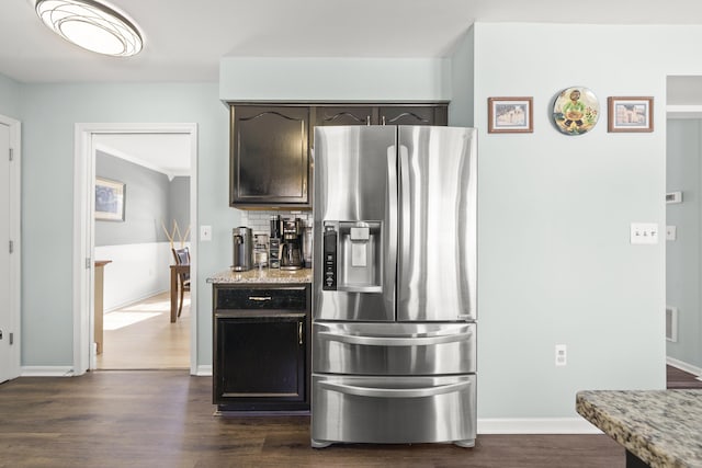 kitchen with light stone countertops, backsplash, dark wood finished floors, and stainless steel refrigerator with ice dispenser